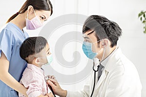 Medical doctor wear mask  and examining  little boy  in clinic