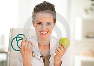 Medical doctor woman showing apple and stethoscope