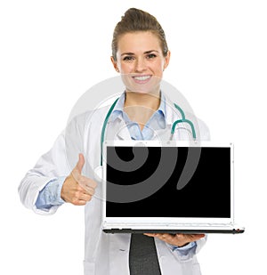 Medical doctor woman showing laptop and thumbs up