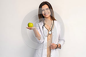 Medical doctor woman smile with stethoscope hold dreen fresh apple in hand. Isolated over white background.