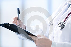 Medical doctor writing and taking notes on clipboard in hospital setting