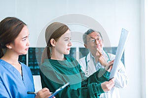 Medical doctors looking at x-rays in a hospital .checking chest x ray film at ward with nurse and female doctor Surgeon.