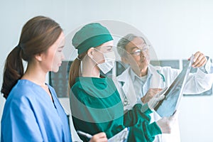 Medical doctors looking at x-rays in a hospital .checking chest x ray film at ward with nurse and female doctor Surgeon.