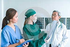 Medical doctors looking at x-rays in a hospital .checking chest x ray film at ward with nurse and female doctor Surgeon.