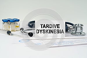 On the medical documents there is a stethoscope, syringe and a business card with the inscription - Tardive Dyskinesia