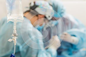 Medical drop counter on the blurry background of the group of doctors in the operating room.