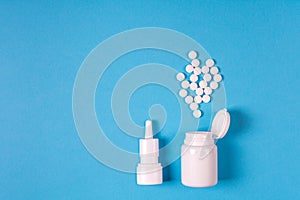 Medical electronic thermometer, medication bottle with pills and spray for nose on blue background.