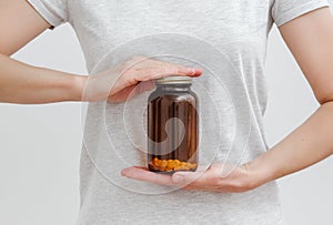 Medical empty brown glass bottle with pills in hands. White background