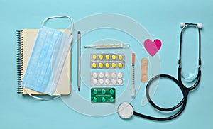 Medical equipment on a blue background. Blisters pills, notepad, stethoscope, syringe, thermometer, manometer. Medical concept, to