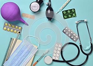 Medical equipment on a blue background. Enema, blisters pills, notepad, stethoscope, syringe, thermometer, manometer. Medical conc