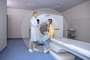 Medical equipment. Female doctor and little girl patient in MRI room in hospital