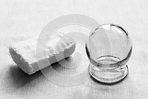 Medical equipment. Retro. Gauze bandage and glass medical jar on white fabric background. Black and white photo.
