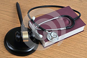 Medical error concept with a stethoscope lying on a book and a judge gavel on a wooden background