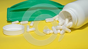 Medical face mask.Close-up,of capsules poured from a jar on a yellow background,medical tablets,drugs,substance for human health.