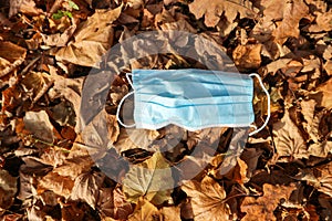 Medical face mask on colorful autumn leafs on the ground coronavirus covid-19 epidemic continues wallpaper