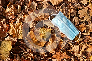 Medical face mask on colorful autumn leafs on the ground coronavirus covid-19 epidemic continues wallpaper