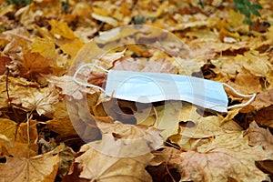 Medical face mask on colorful yellow autumn maple leafs coronavirus covid-19 epidemic continues wallpaper