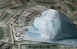 Medical face mask and dollar banknotes, world coronavirus epidemic and economic losses concept