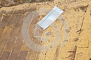 Medical face mask on the floor in the street.Disposable Face Mask.Used Surgical masks haphazardly strewn on pavement.Improperly photo