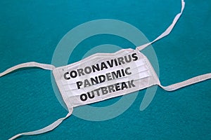 medical face mask with text coronavirus pandemic outbreak on blue background. COVID-19, Wuhan novel corona virus disease 2019-nCoV