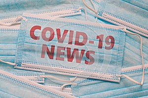 Medical face mask and text with news headline Covid-19. Latest news on coronavirus