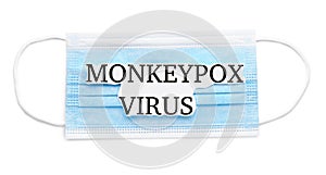 Medical face mask with words Monkeypox Virus on white background, top view