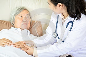 Medical female doctor or nurse holding senior patient hands and comforting her at hospital bed or home,hand of elderly woman with