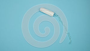Medical female tampon on a blue background. Hygienic white tampon for women. Cotton swab. Menstruation, means of protection.