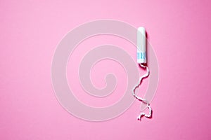 Medical female tampon on a pink background with copy space. Hygienic white tampon for women. Cotton swab. Menstruation, means of