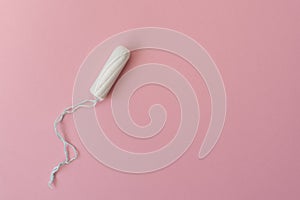 Medical female tampon on a pink background. Hygienic white tampon for women. Cotton swab. Menstruation, protection concept, flat