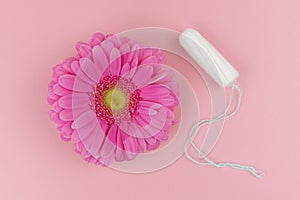 Medical female tampon with a pink gerbera on a pink background. Hygienic white tampon for blood period. Cotton swab. Menstruation