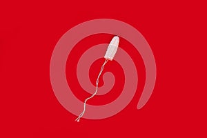 Medical female tampon on a red background. Hygienic white tampon for women. Cotton swab. Menstruation  means of protection