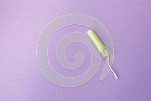 Medical female tampon on a violet background. Hygienic white tampon for women. Cotton swab. Menstruation, protection concept, flat