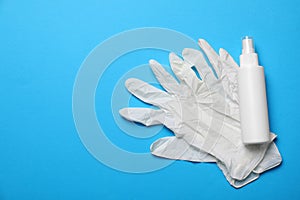 Medical gloves and hand sanitizer on light blue background, flat lay with space for text. Safety equipment