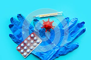 Medical gloves and red coronavirus model on blue background. photo
