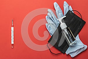 Medical gloves surgical mask, sanitizer gel thermometer - Virus protection equipment on red background. Pathogen respiratory