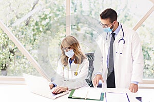 Medical group wearing face masks while working together in hospital photo