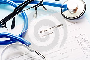 Medical and healthcare concept. Close up image of a medical history form and a doctors stethoscope with glasses