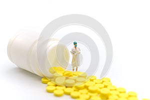 Medical and Healthcare Concept. Closeup doctor miniature figure people with file standing with yellow pills with bottle on white