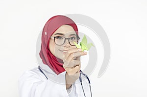 medical healthcare concept, young doctor standing with stethoscope, holding origami bird on white background