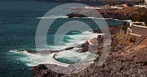 Medical helicopter landing on rocky volcanic shore for rescue operation at stormy ocean beach. Aviation provides first