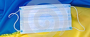 A medical hygienic mask lies on the yellow-blue flag of Ukraine