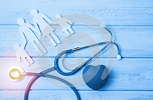 Medical Insurance Concept. Family cutout and Stethoscope on wooden background. Blue tonned