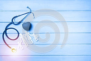 Medical Insurance Concept. Family cutout and Stethoscope on wooden background. Blue tonned