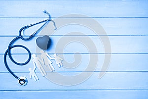 Medical Insurance Concept. Family cutout and Stethoscope on wooden background. Blue tonned