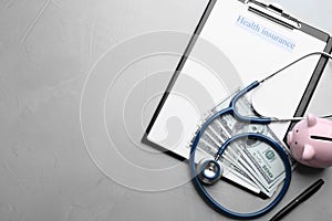 Medical insurance form with money, stethoscope and piggybank on grey background, flat lay