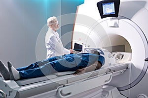 In Medical Laboratory Senior Radiologist Controls MRI or CT or PET Scan with Male Patient Undergoing Procedure