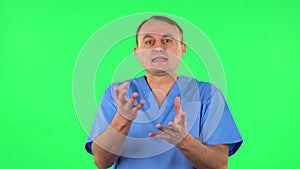 Medical man emotionally looks at something, comments and then disappointedly gives up hands. Green screen