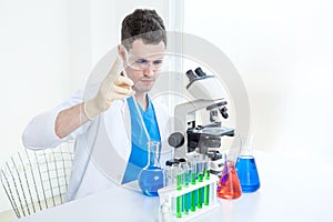 Medical man with or scientific researcher or scientist working with a microscope and test tubes in a laboratory
