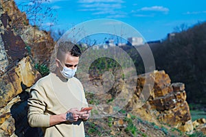 Medical mask as protection against coronavirus. guy in the mountains isolated from coronavirus. looking at his phone